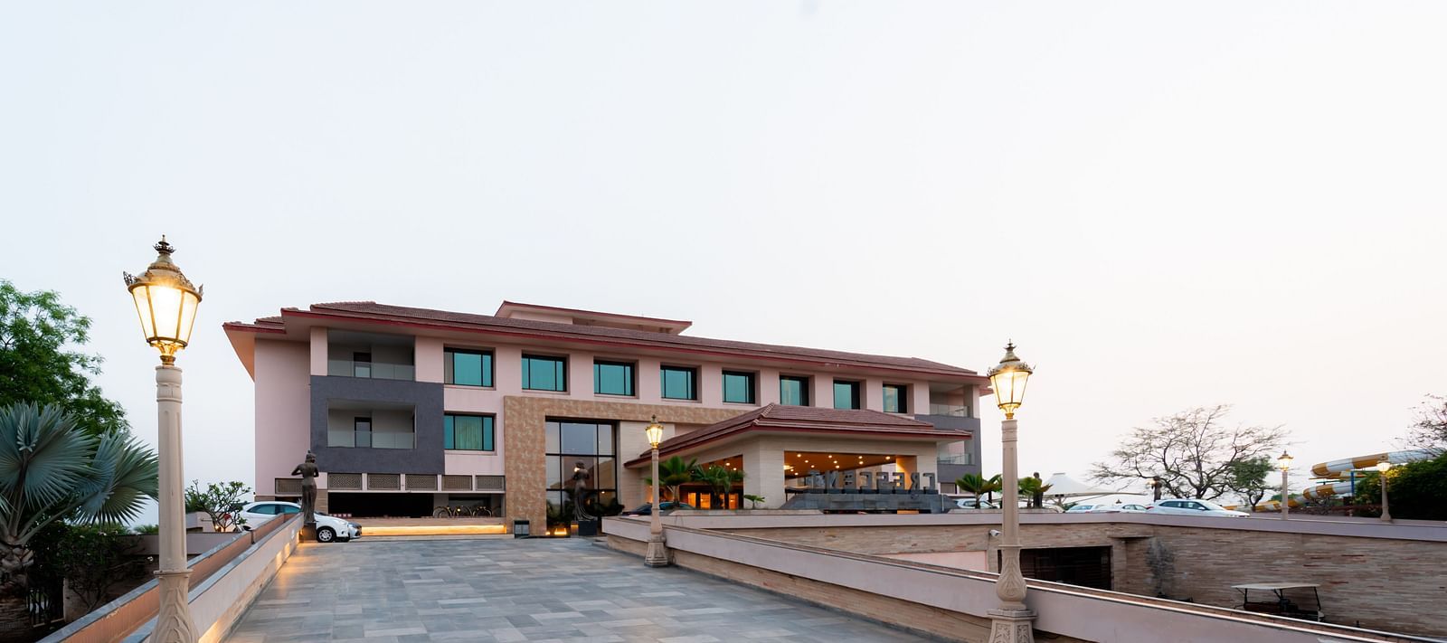 Facade view of Crescent Spa & Resort, Indore, set against a backdrop of a cloudy sky, showcasing its grand architecture
