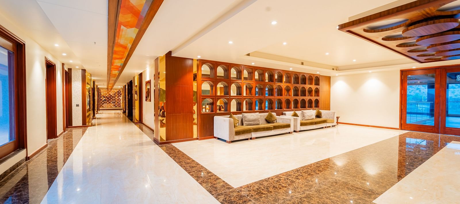 obby area with a sleek tiled floor, warm lighting, and large, comfortable furniture at Crescent Spa & Resort, Indore