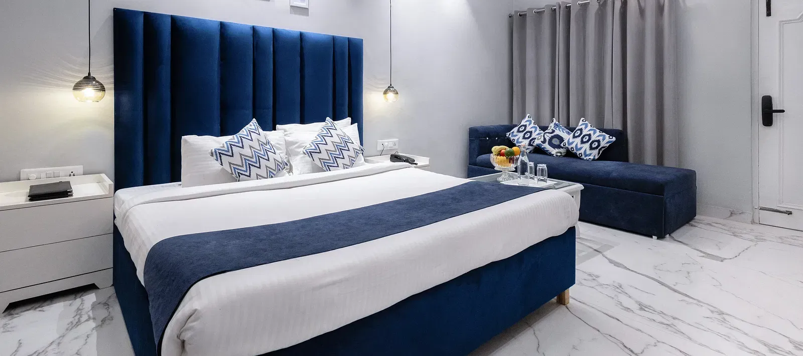 Super Deluxe Room featuring a king size bed with a blue accent, a seating area, and a marble floor. - Hotel Downtown17, Chandigarh