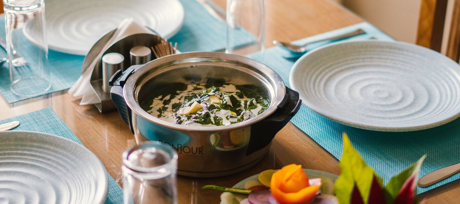 A close-up view of a table with a dish placed in the middle, and plates and glasses on the sides at BluSalzz Villas - The Green Roof, Bhimtal.