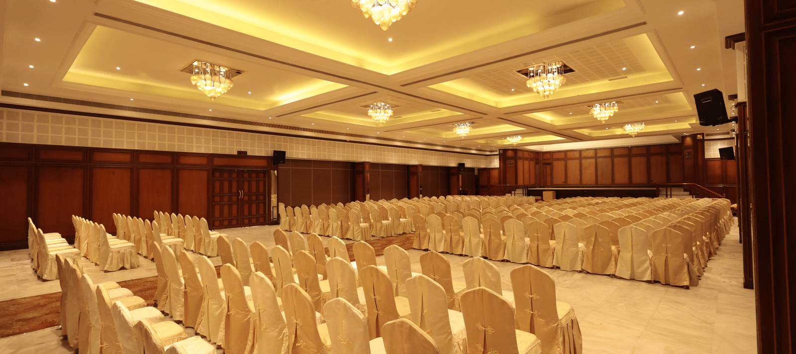 A diagonal view of the banquet hall from behind, with decorated chairs and yellow lighting | Cenneys Gateway