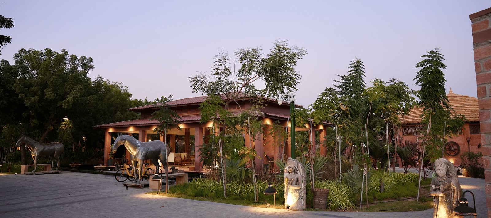 Facade of Surpura Bagh with trees surrounding it and a pathway leading to the reception under evening sky