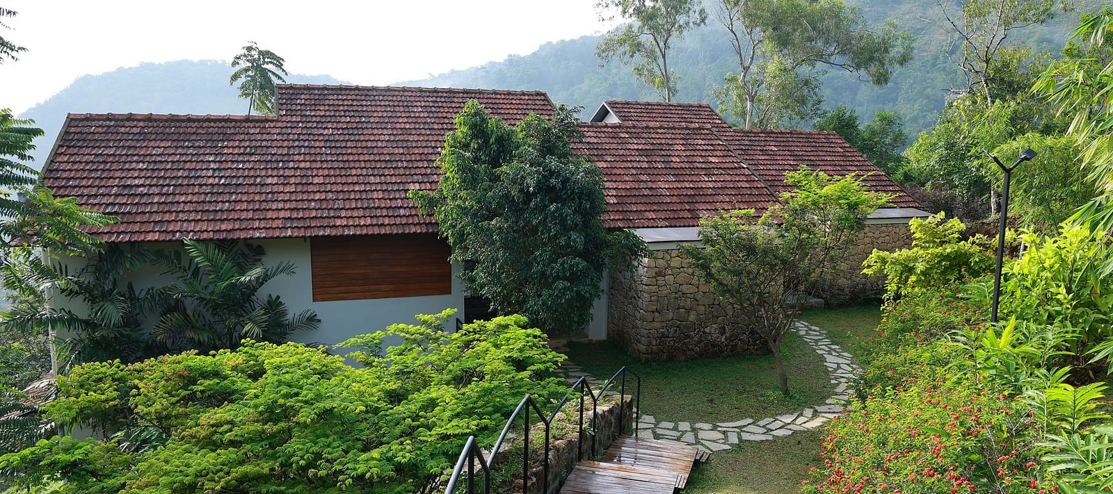  A building with a tiled roof at Vaastha Vagamon, nestled amidst lush greenery and offering expansive valley views.