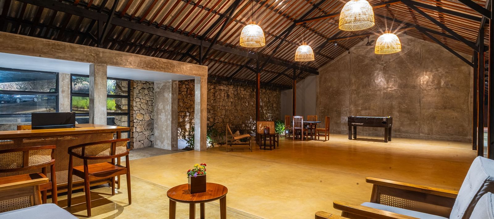  A common area at Vaastha Vagamon with exposed beams, pendant lighting, seating, and a bar counter.