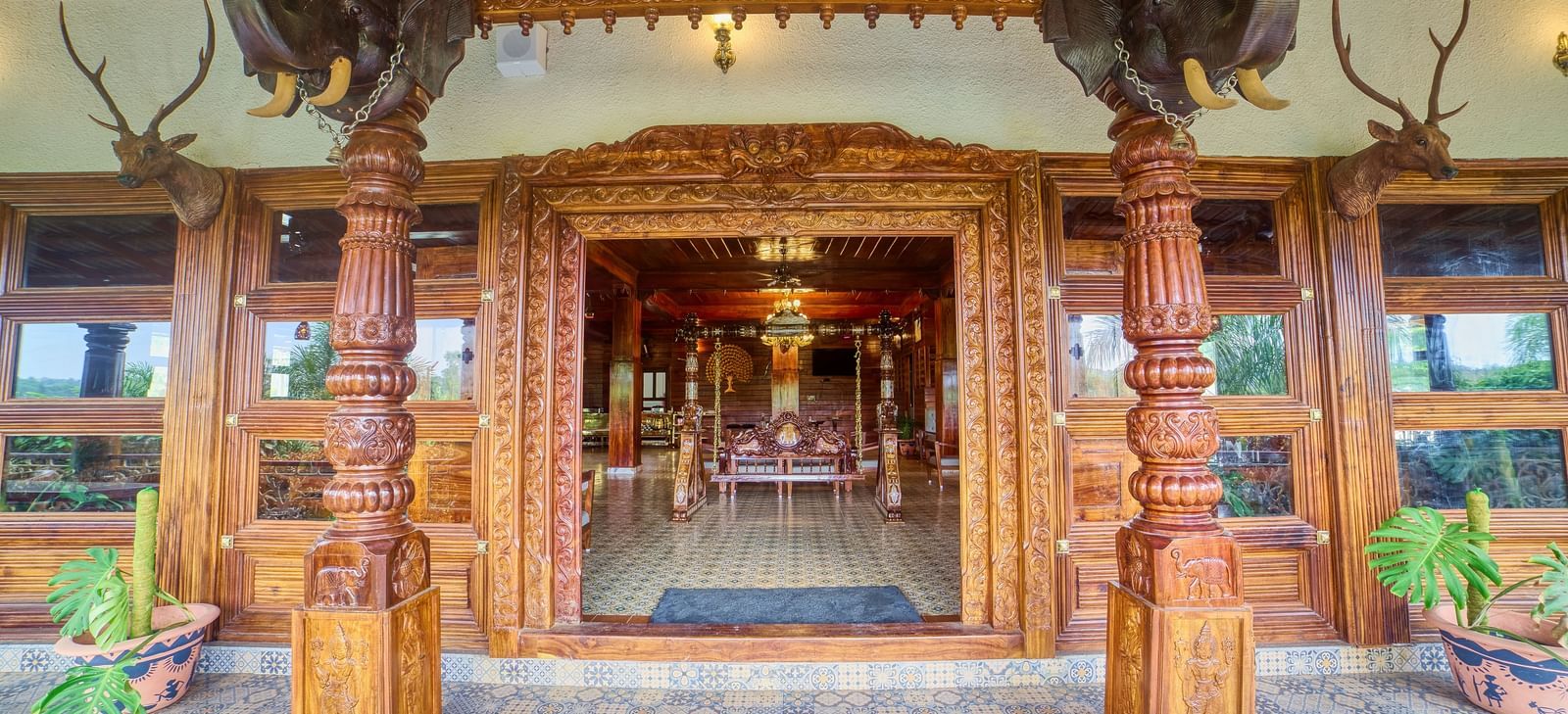 The grand entrance of a building with intricate wooden carvings and columns, leading into a warmly lit interior. - Vintage Trails by Ilara