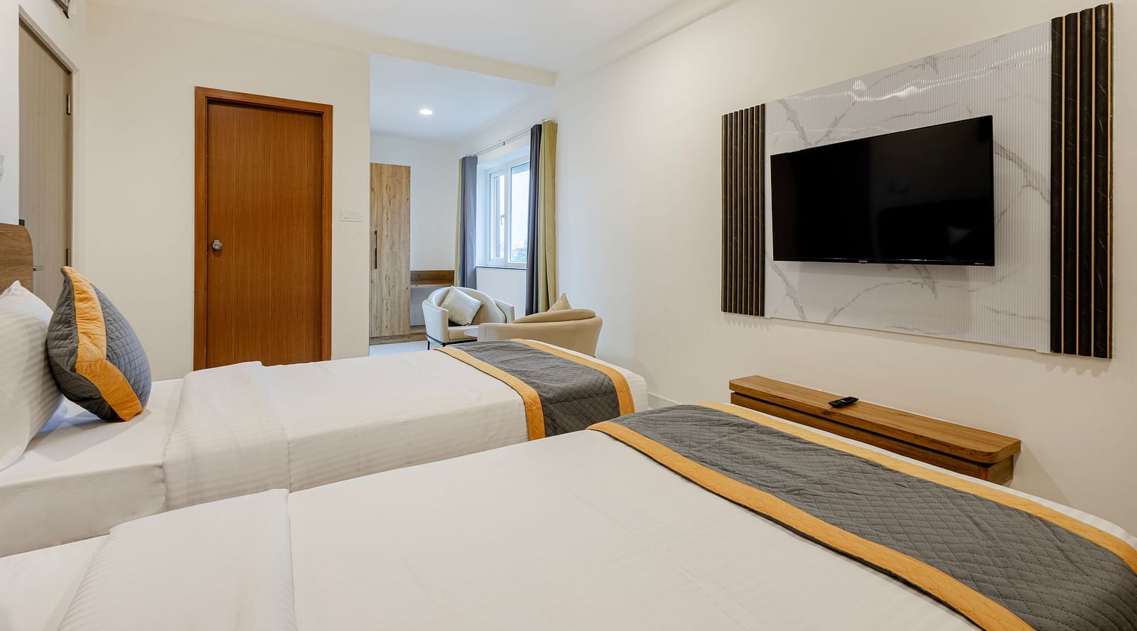 Minimalist bedroom with two single beds, flat-screen TV, and ambient lighting at Lemonridge Hotels, IDPL Balanagar.