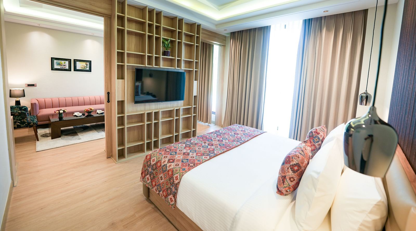 An image showcasing a bedroom of a suite in Kangra in the foreground, with the living area visible in the background - NAMAMI BY ZENQ BANKHANDI