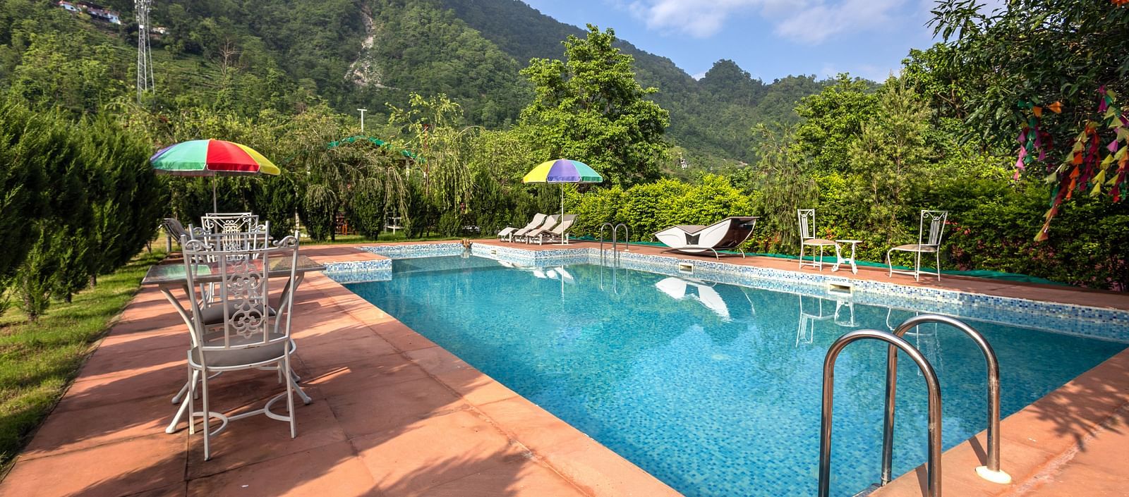 swimming pool with chairs, tables and canopies around it - neer ganga Resorts