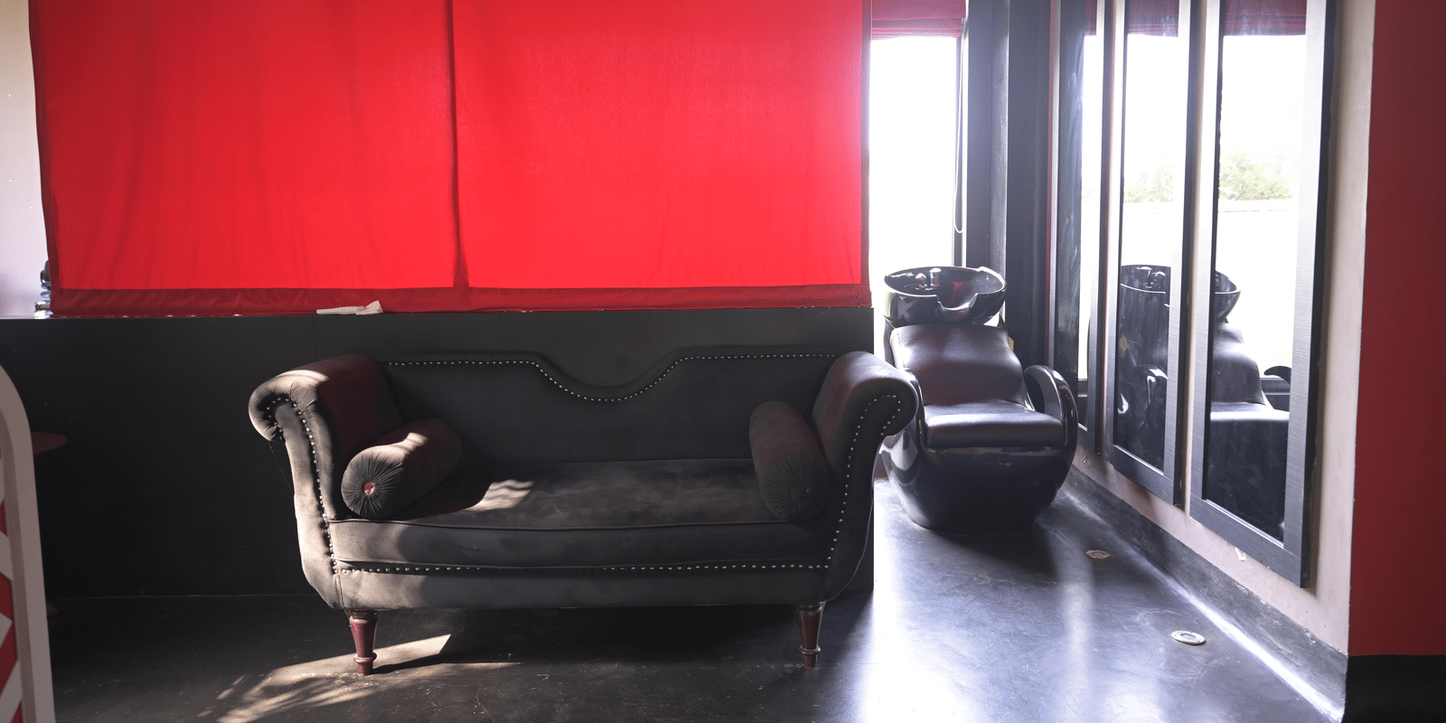 A stylish relaxation lounge with curtains, dark flooring, and comfortable seating at Hotel Sonar Bangla Mayapur.