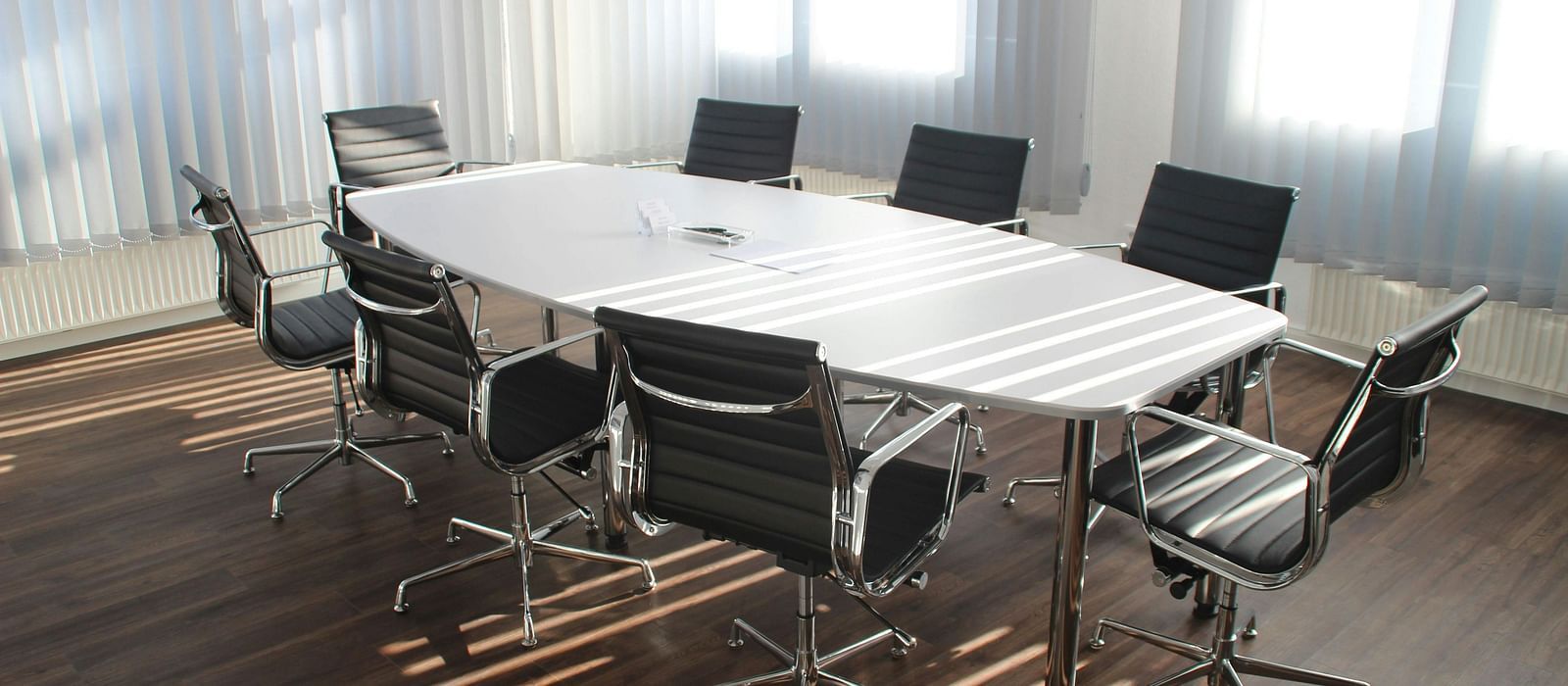 A well-appointed Boardroom featuring a broad table with chairs neatly arranged around it, offering a professional setting for meetings