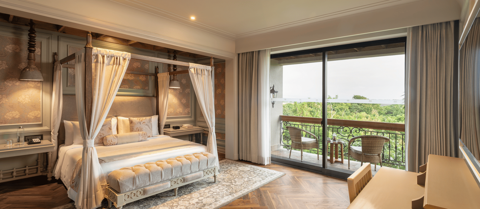 Full-view shot of the bedroom at the Evren Suite featuring wooden flooring and a balcony that opens to the verdant views of the frest at The Evren, Vagator.