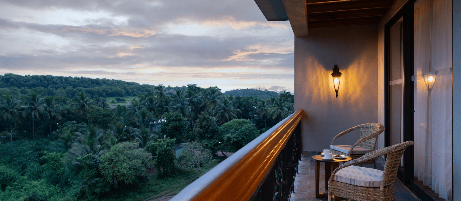 The balcony at the Evren Suite overlooking at the lush green forests with a cloudy evening sky in the background at The Evren, Vagator.