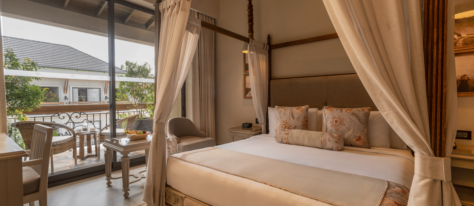 A plush double bed in the Premium Room at The Evren, Vagator, with a balcony beside it featuring a sit-out area.