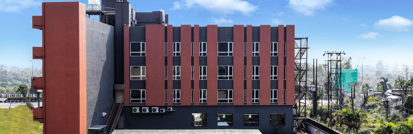 A modern hotel building with a swimming pool and green lawn under a partly cloudy sky | The Citi Residenci Hotel Banskopa