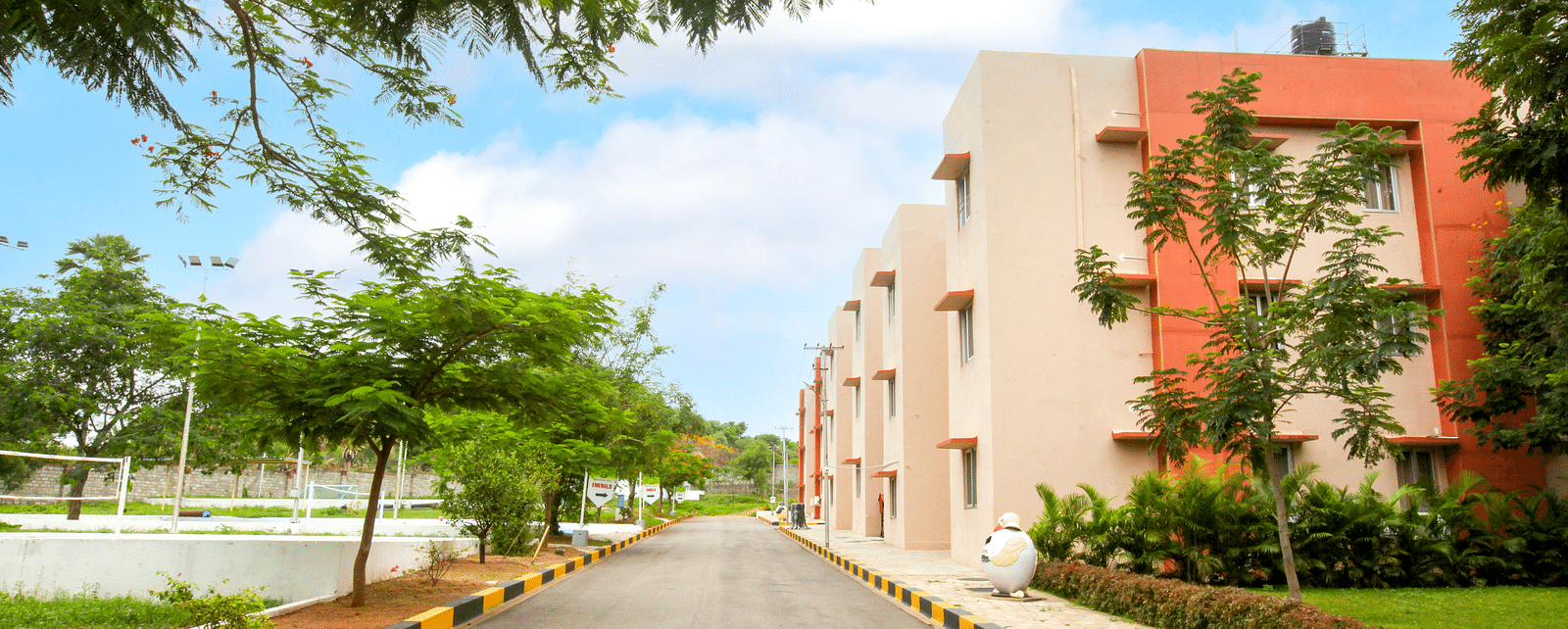 A view of Greens Inn by a road, surrounded by trees - Convenient Location in Hyderabad.