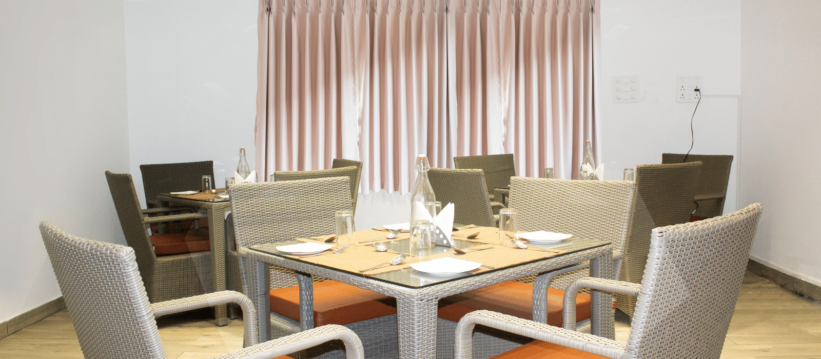 A dining table with orange-coloured cushions on the chair at the Spice and Slice Restaurant at WOW Naturefull Resorts, Yercaud.
