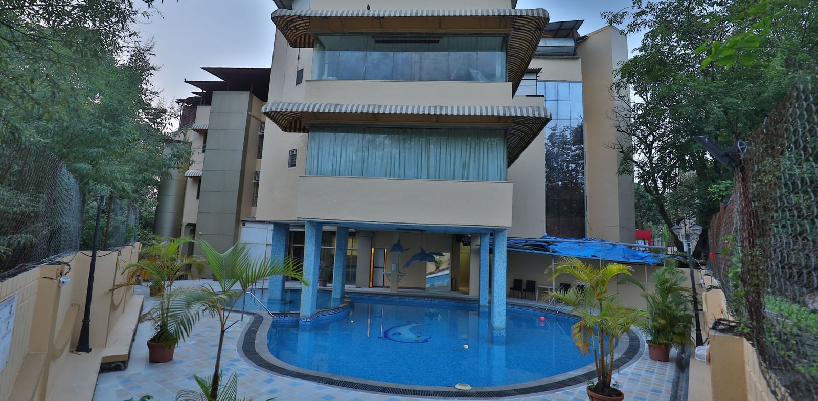 The exterior of a multi-story hotel building with a visible swimming pool in the foreground - Retreat Heritage, Lonavala
