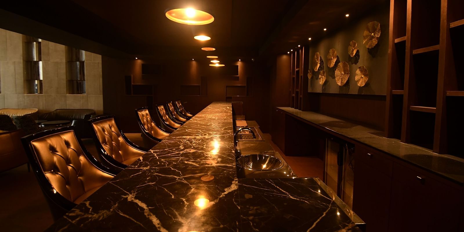 A large marble table surrounded by chairs, complemented by warm lighting