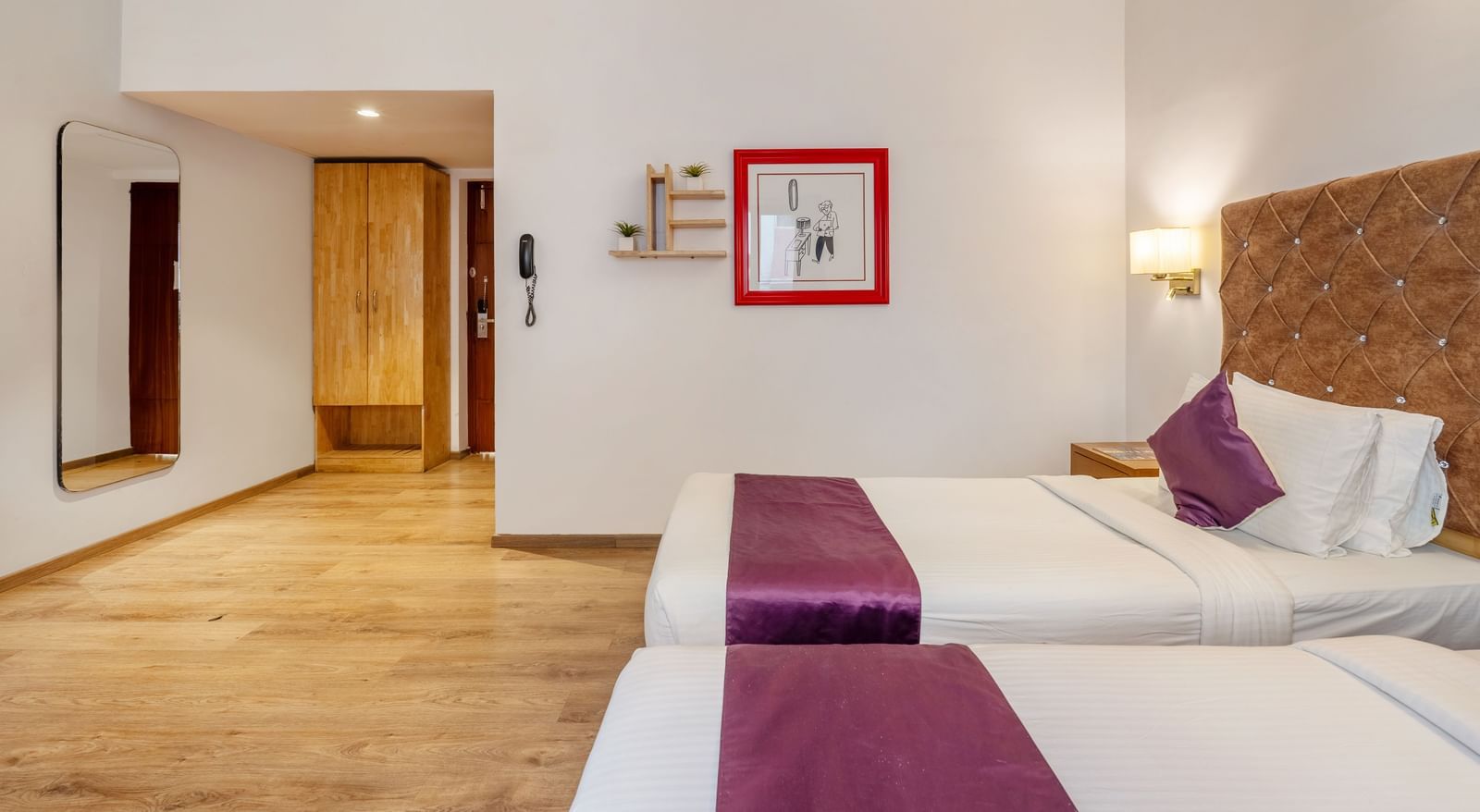 A spacious hotel room with 2 single beds, a frame, a mirror attached to the wall and a wall-mounted light – Monday Hotels HITEC City, Hyderabad