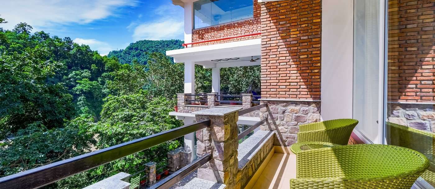 Balcong with seating area and views of the lush plants at Summit By The Ganges Beach Resort & Spa, Rishikesh