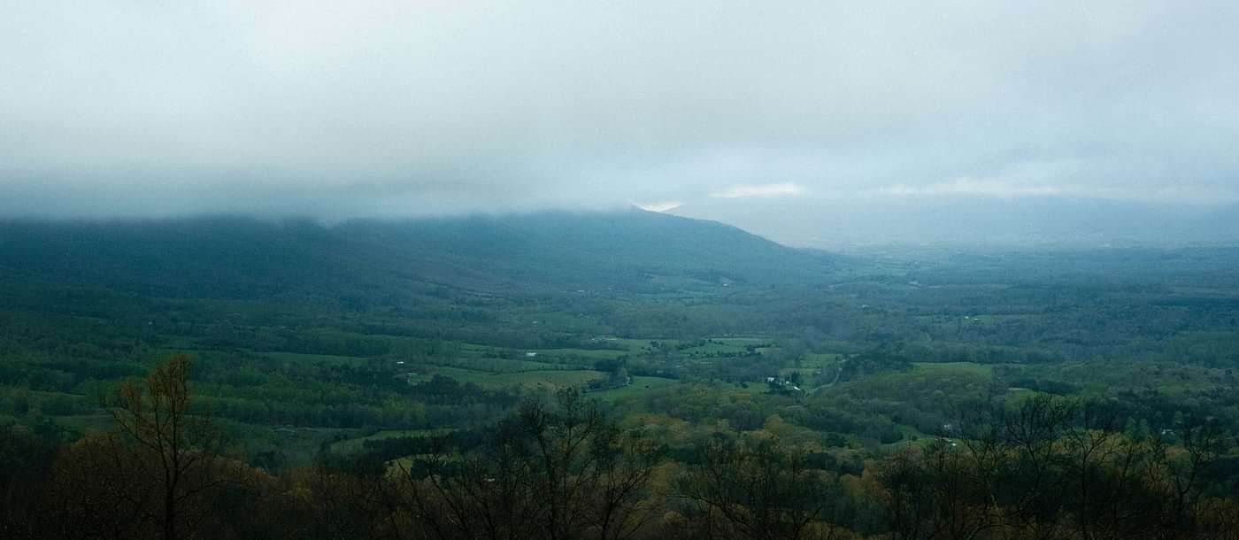 A scenic mountain landscape adorned with lush greenery, draped in drifting clouds, offering a breathtaking and tranquil view