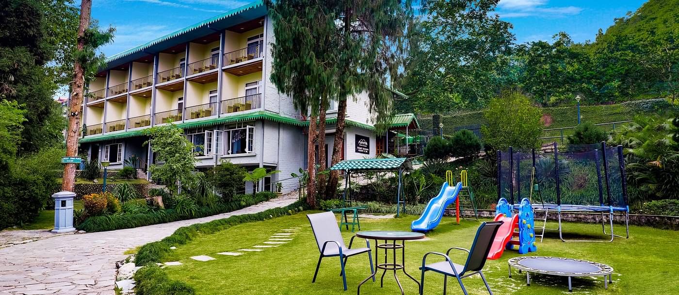 outdoor play area for children with the facade of summit barsana resort and spa in kalimpong