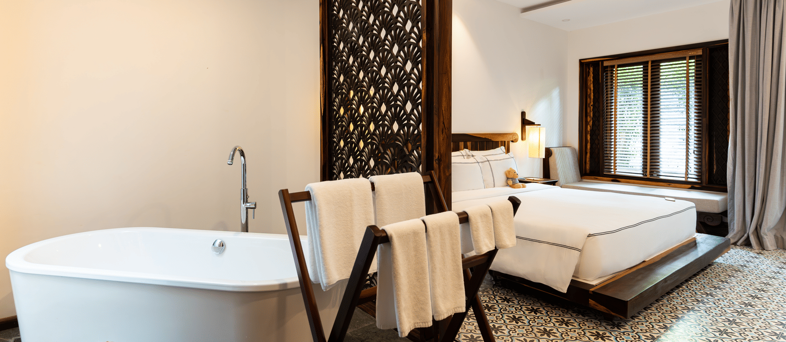 Bedroom at Alibu Resorts, Nha Trang featuring a double size bed, a lounge bed near the window, and a bathing tub with towels.