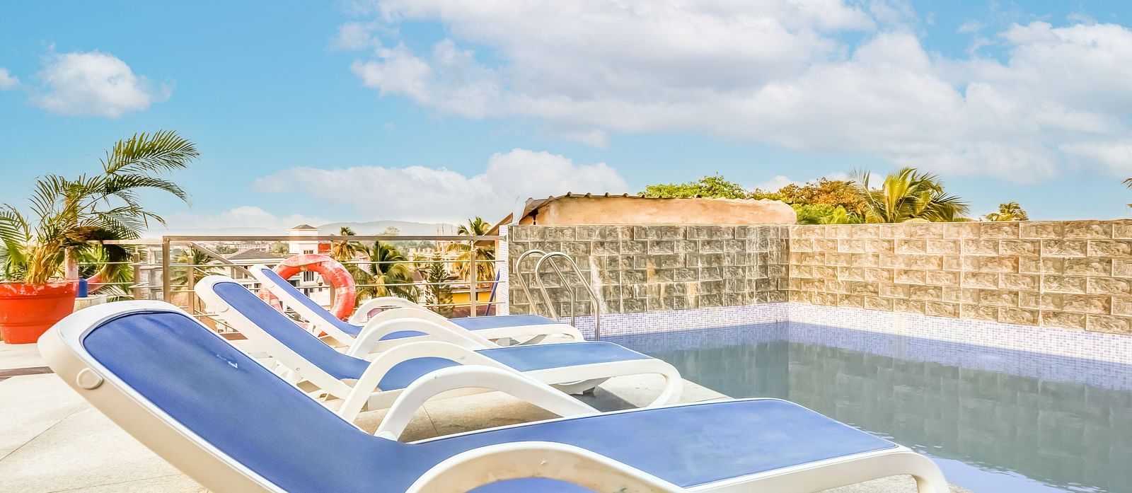  Pool area featuring a reclining chair nearby, set against a backdrop of a partly cloudy sky