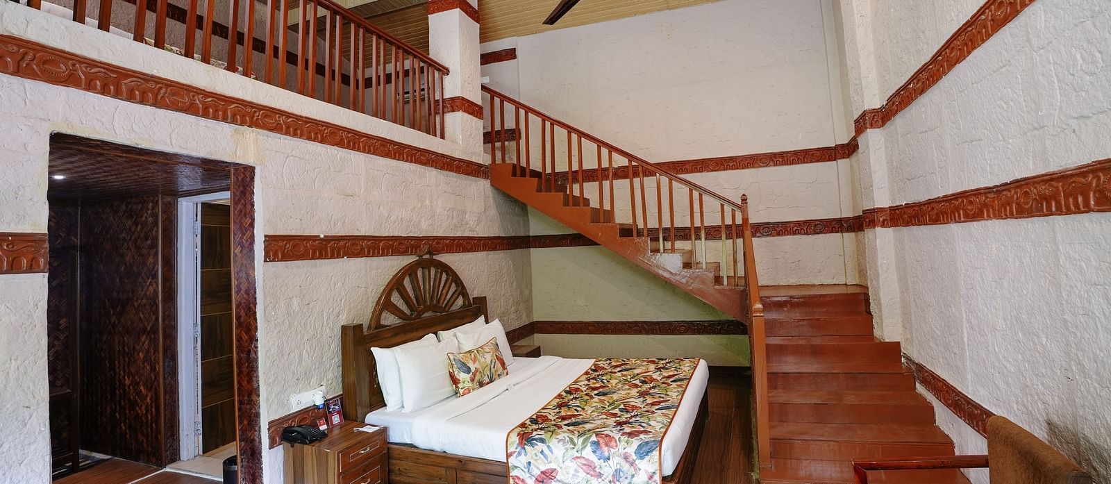 Duplex ethnic villa featuring a spacious bedroom and staircase leading to an additional room at Summit Green Lake Tea Resort & Spa, Kaziranga