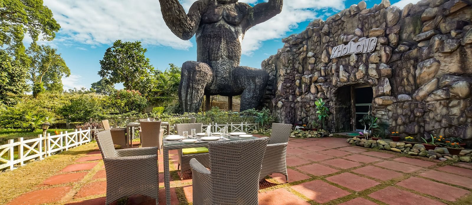 Outdoor Kholong restaurant with a giant gorilla holding a rock in one hand and a helicopter in the other