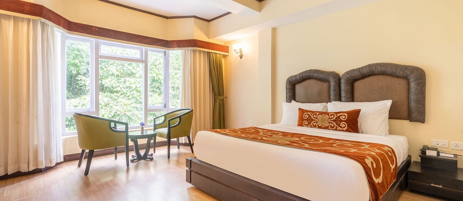 king size bed  with chairs near balcony of deluxe bed at Summit Lillium Hotel & Spa, Kalimpong