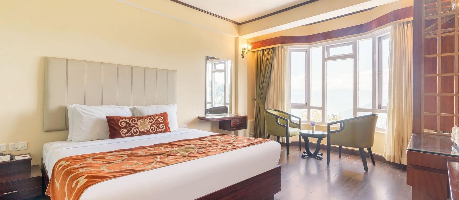 king size bed and chairs in the background near balcony of premium room at Summit Lillium Hotel & Spa, Kalimpong