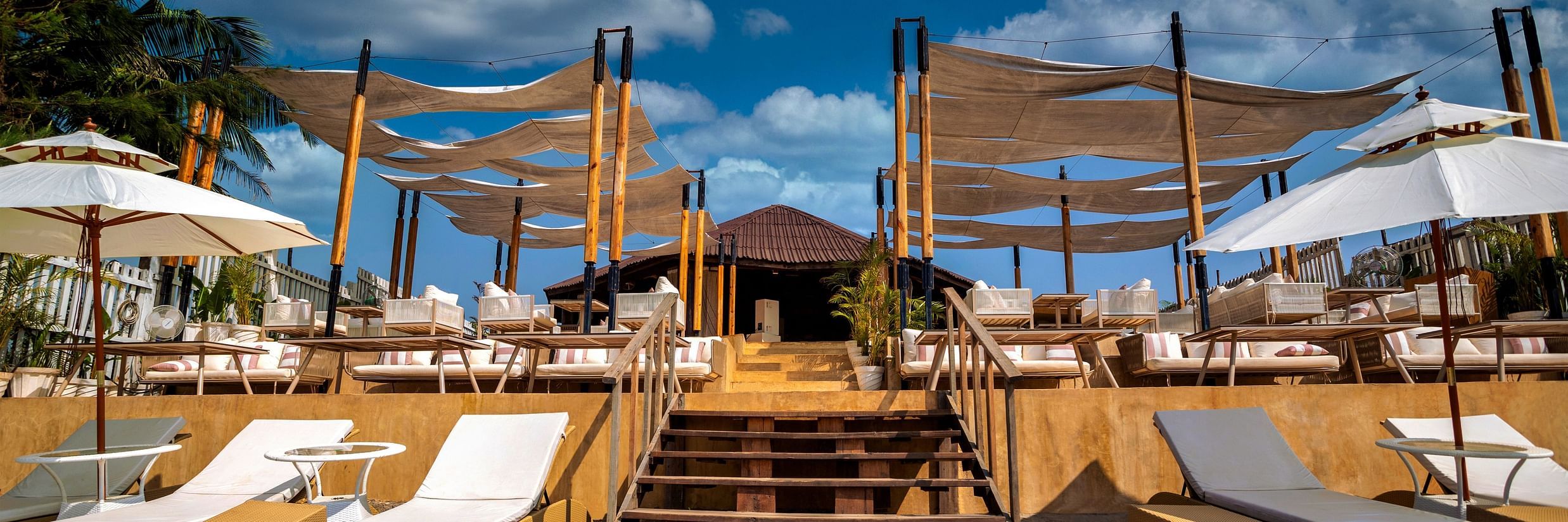 front view of the entrance of the saz on the beach restaurant featuring white coloured sun loungers at the entrance