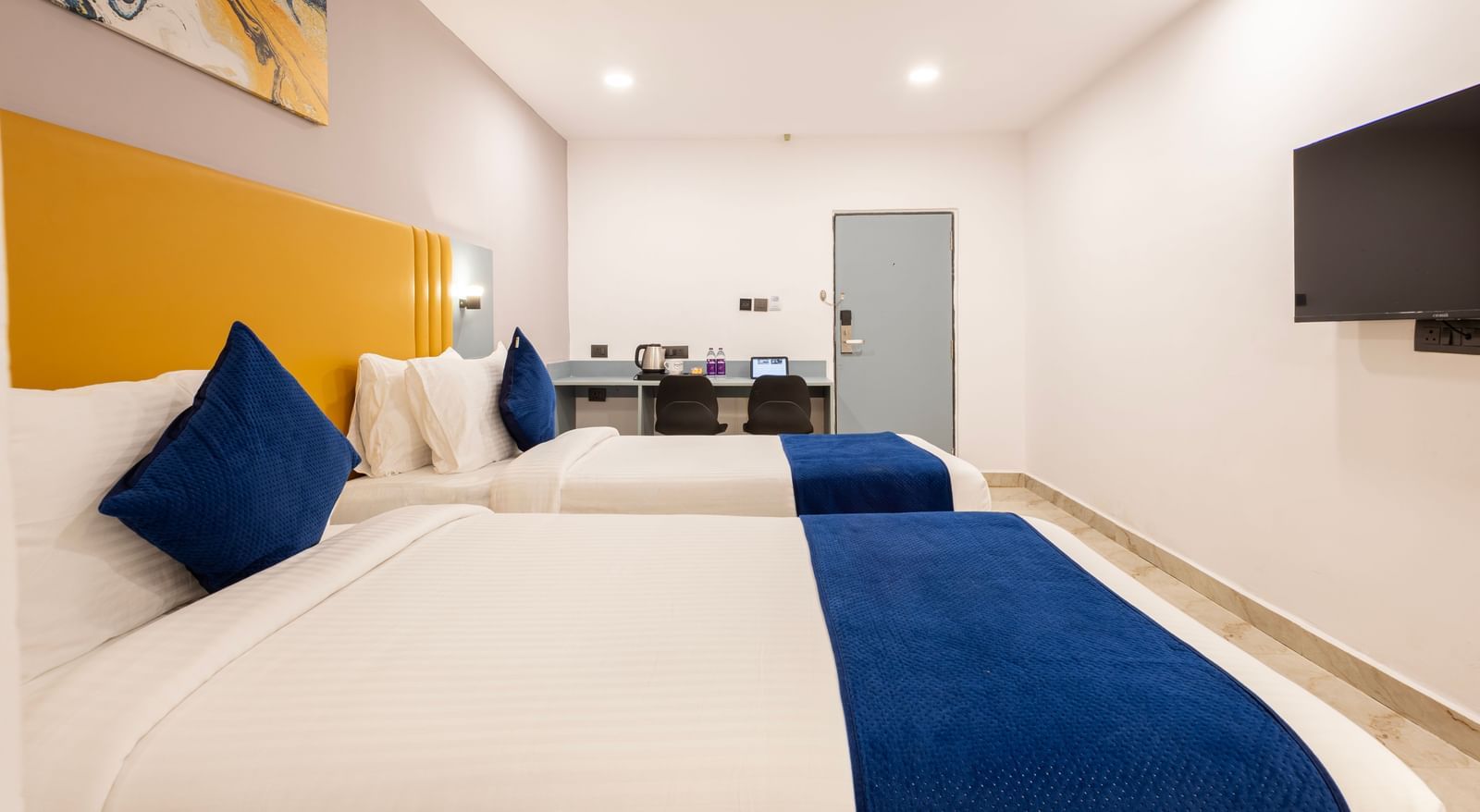Close up side view of Superior Room featuring a bed with blue and white bedding, a yellow headboard, and modern furnishings including a desk and TV - Beestay Hotel Financial District, Hyderabad