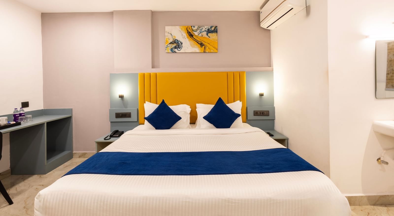 Close up of a modern Premium Room with a bed featuring blue accents, a work desk area, and a door on the left  - Beestay Hotels Financial District, Hyderabad 