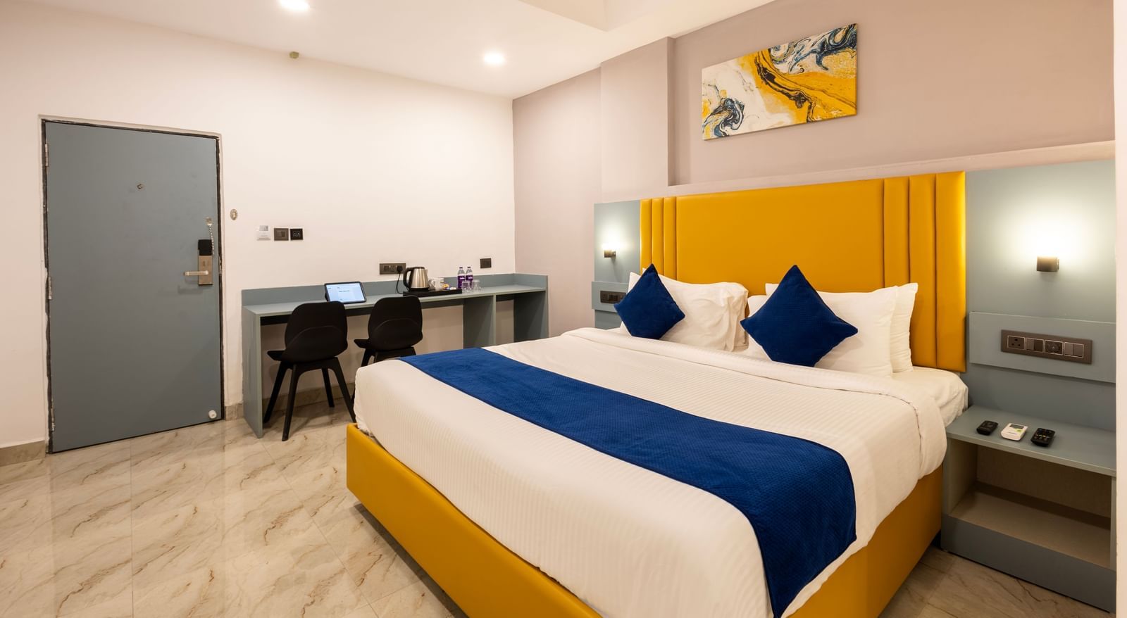 Overview of a modern Premium Room with a bed featuring blue accents, a work desk area, and a door on the left  - Beestay Hotels Financial District, Hyderabad 