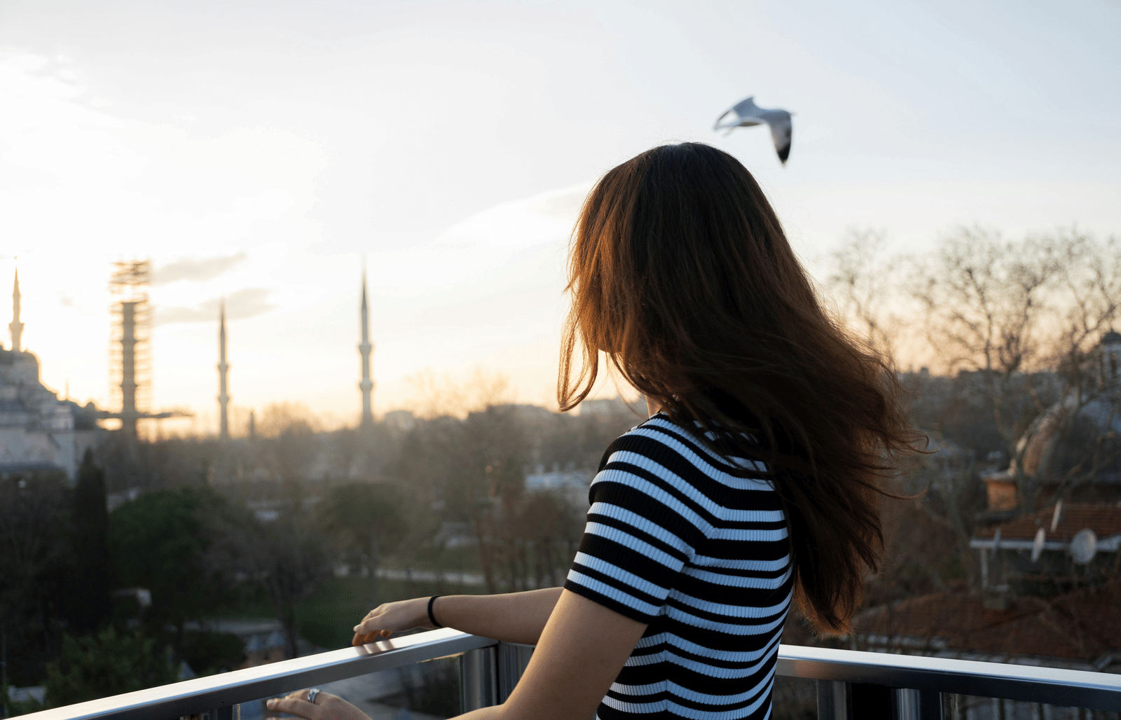 View of a woman standing in a balcony and watching the city.