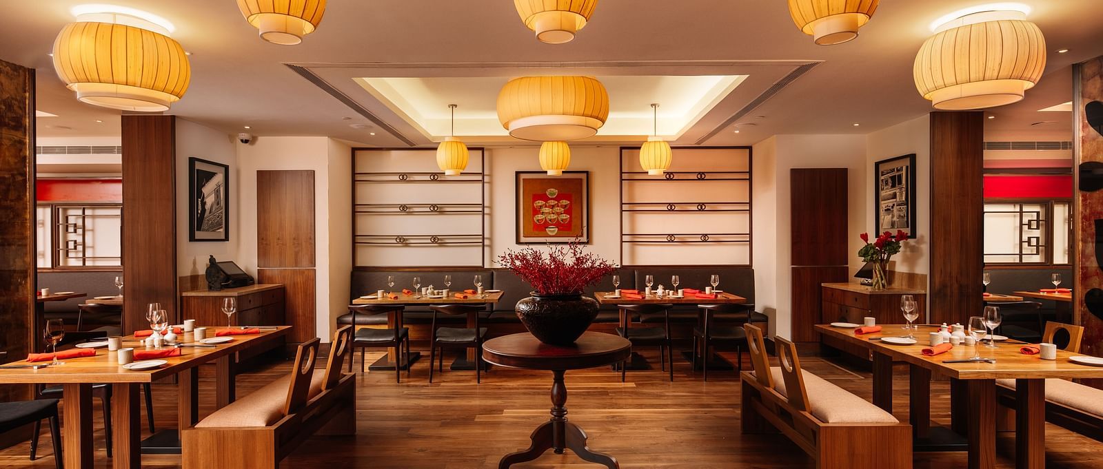 A restaurant with wooden seating arrangements and lantern hanging from the ceiling at The Raintree Hotel, St. Mary's Road.