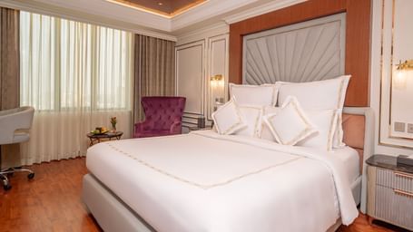 King size bed in a room at Accord Metropolitan with two side tables and wall panelling.