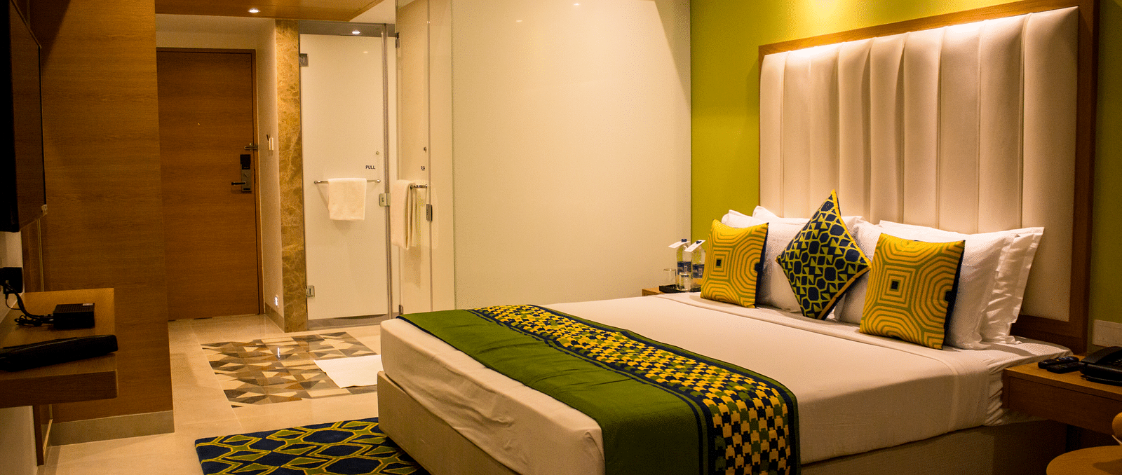 A room with a bed and  pillows arranged on it  along with  a side table | Regency Tirunelveli By GRT Hotels