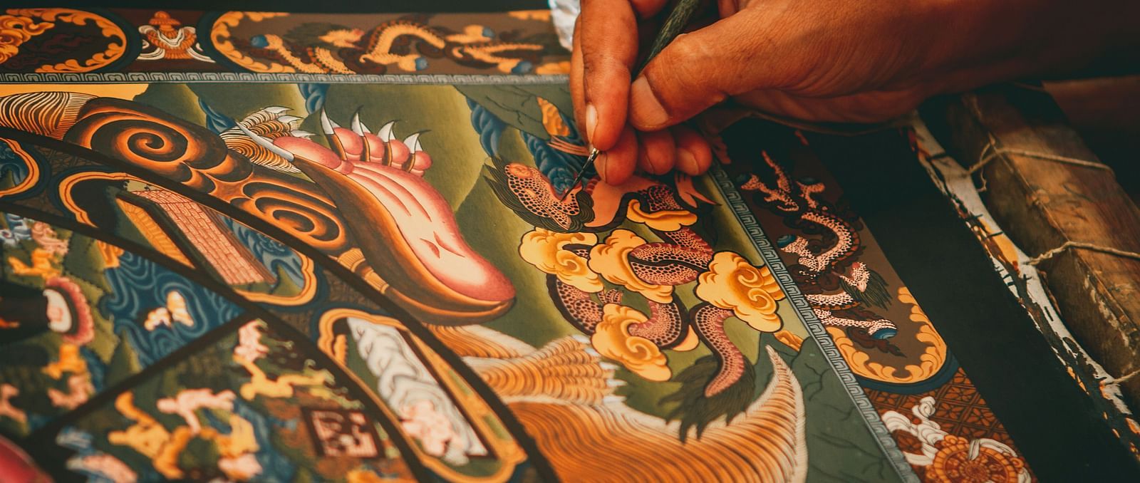 A close up shot of a person hand seen painting a Thangka painting