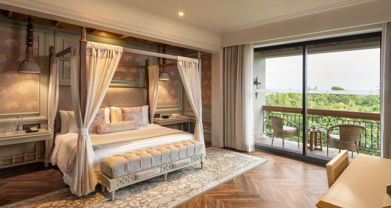 Full-view shot of the bedroom at the Evren Suite featuring wooden flooring and a balcony that opens to the verdant views of the frest at The Evren, Vagator.