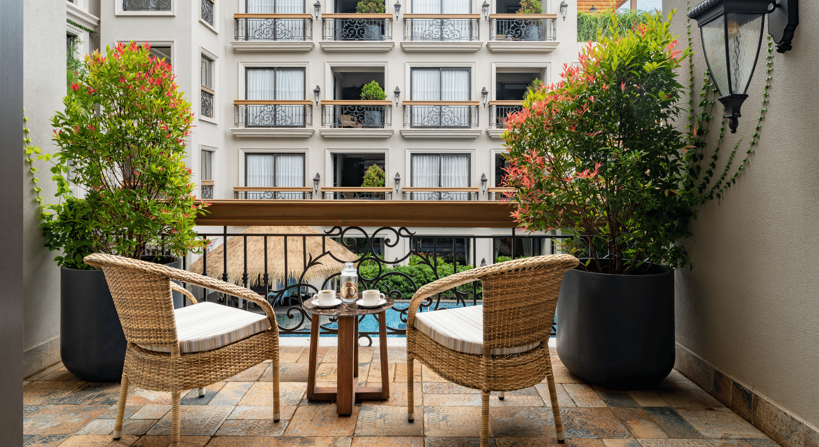 Back shot of the outdoor sit-out area in a balcony of the Premium Room overlooking the swimming pool.