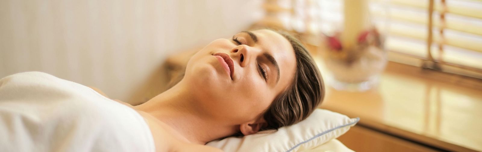 a woman lying down on a bed all relaxed in a brightly lit room