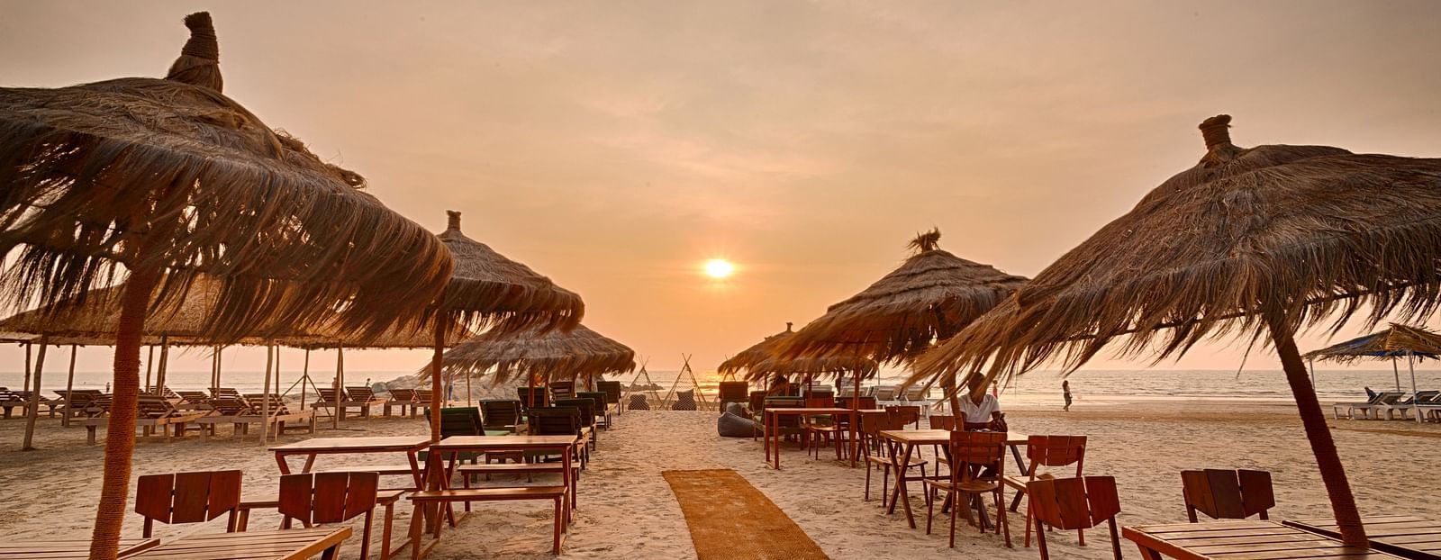 Sunset dining setup with beach chairs and umbrellas at Royale Amata by the Beach Restaurant