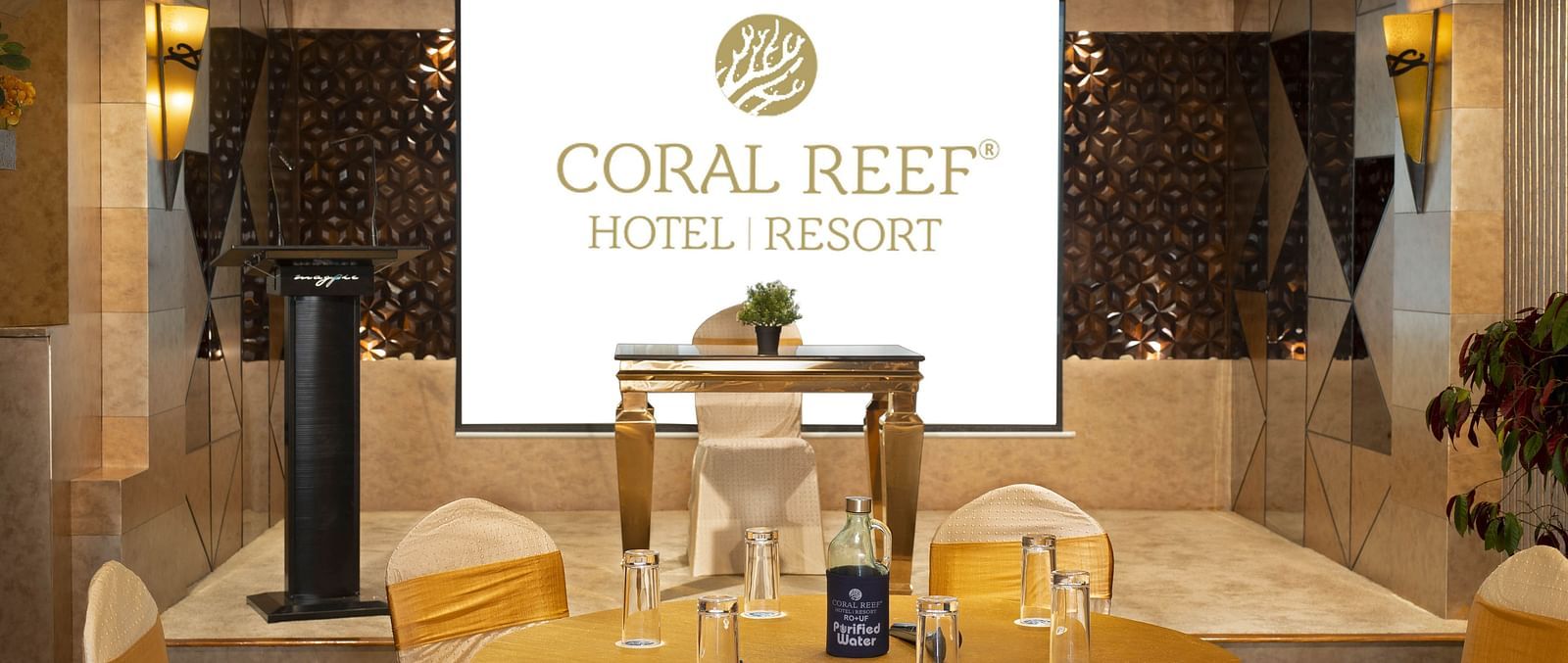 Image of Mosaic Hall at Coral Reef Hotel and Spa in Port Blair featuring seating arrangement with golden fabrics in front of the projector screen 