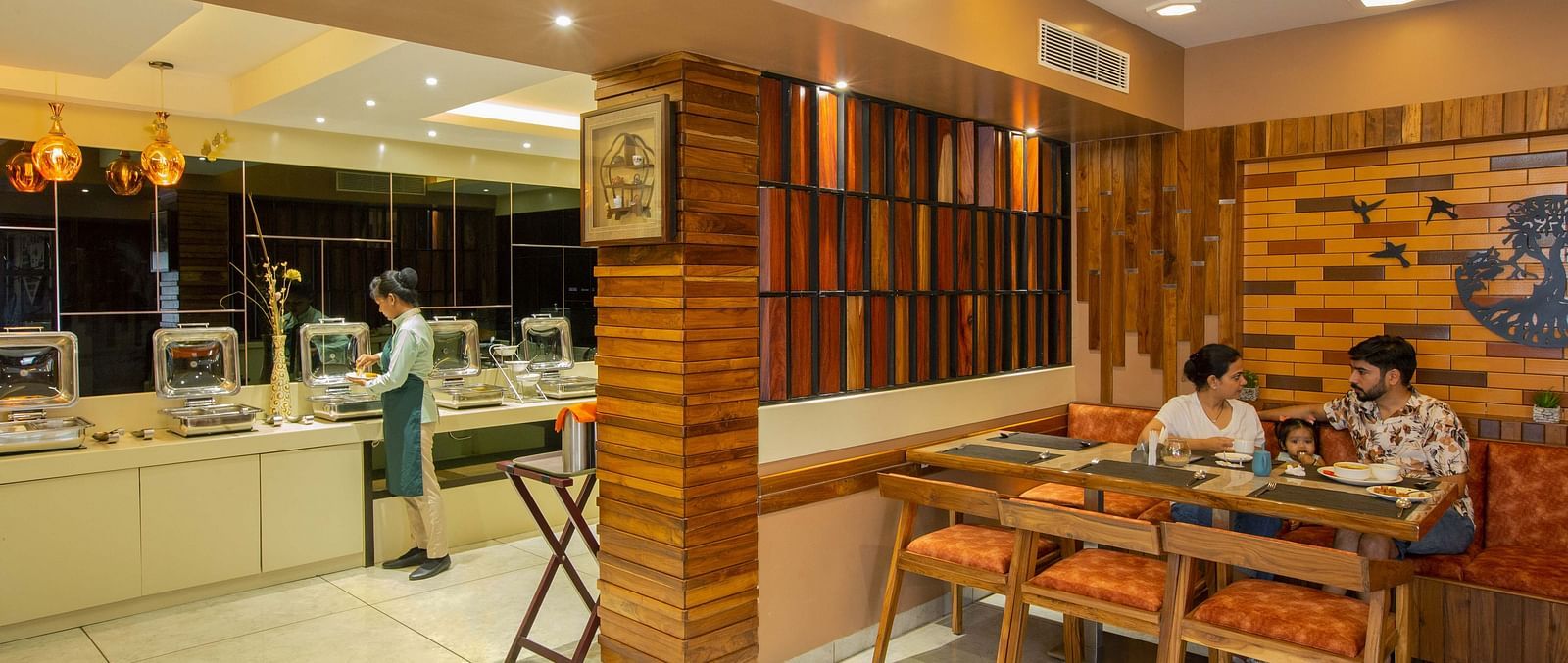 Image of two people along with a child in the middle dining at Honeycomb Restaurant at Coral Reef Hotel & Spa in Port Blair