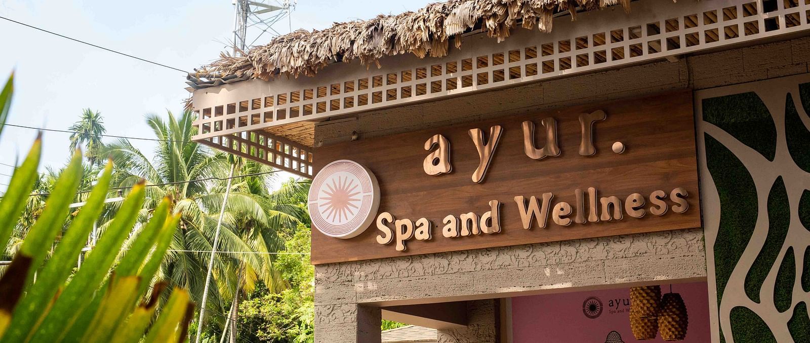 A sign for the Ayur Spa and Wellness centre at Coral Reef Hotel & Spa in Havelock with an elegant design featuring a calm, relaxing atmosphere. The surrounding greenery adds to the peaceful setting - Coral Reef Resort & Spa, Havelock