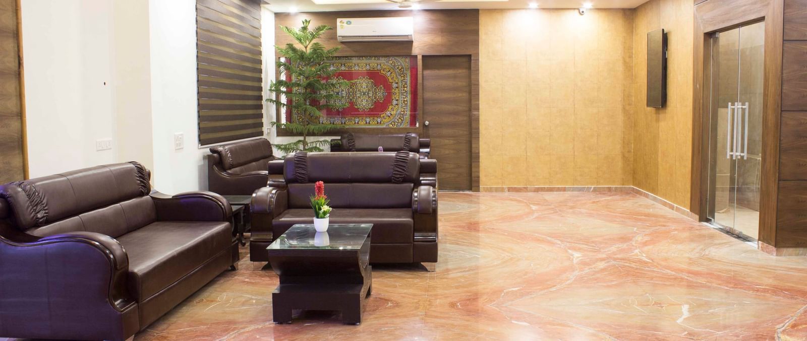 A hotel lobby with marble flooring and an elevator area | Daksh The Madhuvan Suites