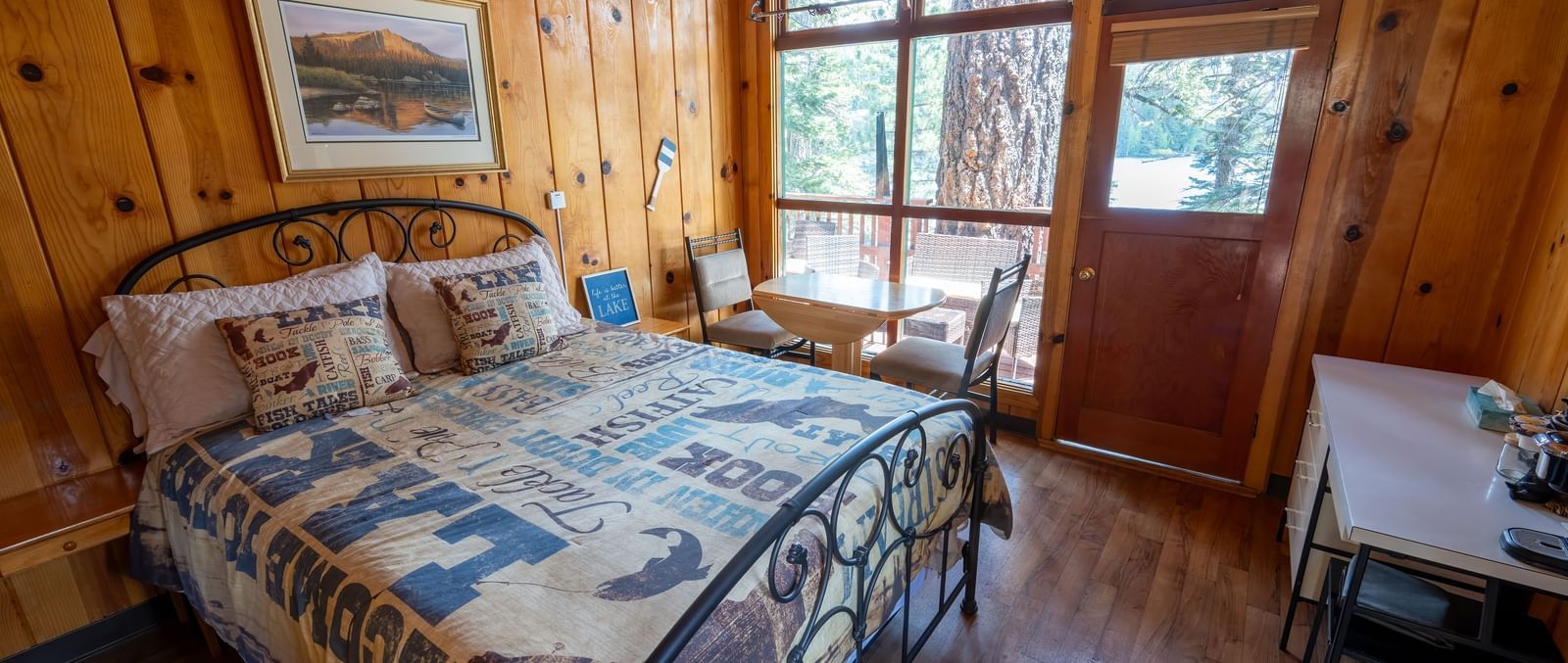 Warmly decorated bedroom with patterned bedding and large windows overlooking trees at Kit Carson Lodge.